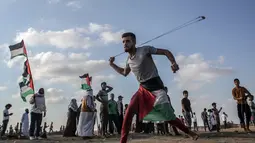 Pria Palestina memakai ketapel untuk melemparkan batu ke arah pasukan Israel saat bentrok di Khan Yunis, Jalur Gaza, Jumat (13/9/2019). Warga menyerukan pencabutan blokade Israel di Jalur Gaza. (SAID KHATIB/AFP)