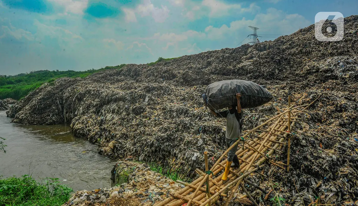 Warga membawa sampah daur ulang melewati lokasi longsor Tempat Pembuangan Akhir (TPA) Cipayung yang menimbun Kali Pesanggrahan di Depok, Jawa Barat, Selasa (30/4/2024). (merdeka.com/Arie Basuki)