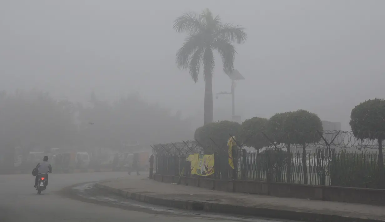 Seorang pria mengendarai sepeda motor di tengah kabut tebal di Kota Lahore, Pakistan timur, pada 13 Desember 2020. Kabut tebal menyelimuti sejumlah kota di Pakistan, sehingga meminimalkan jarak pandang dan mengganggu lalu lintas jalan. (Xinhua/Sajjad)