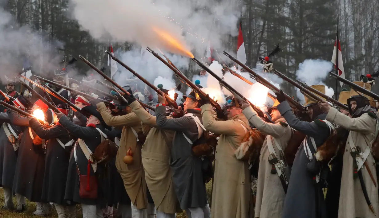 Sejumlah peserta berpakaian seperti tentara Rusia dan Prancis tahun 1812 melespaskan tembakan saat melakukan adegan pertempuran di Belarus (26/11). Perang tersebut antara pasukan tentara Napoleon melawan pasukan Rusia. (AP Photo/Sergei Grits)