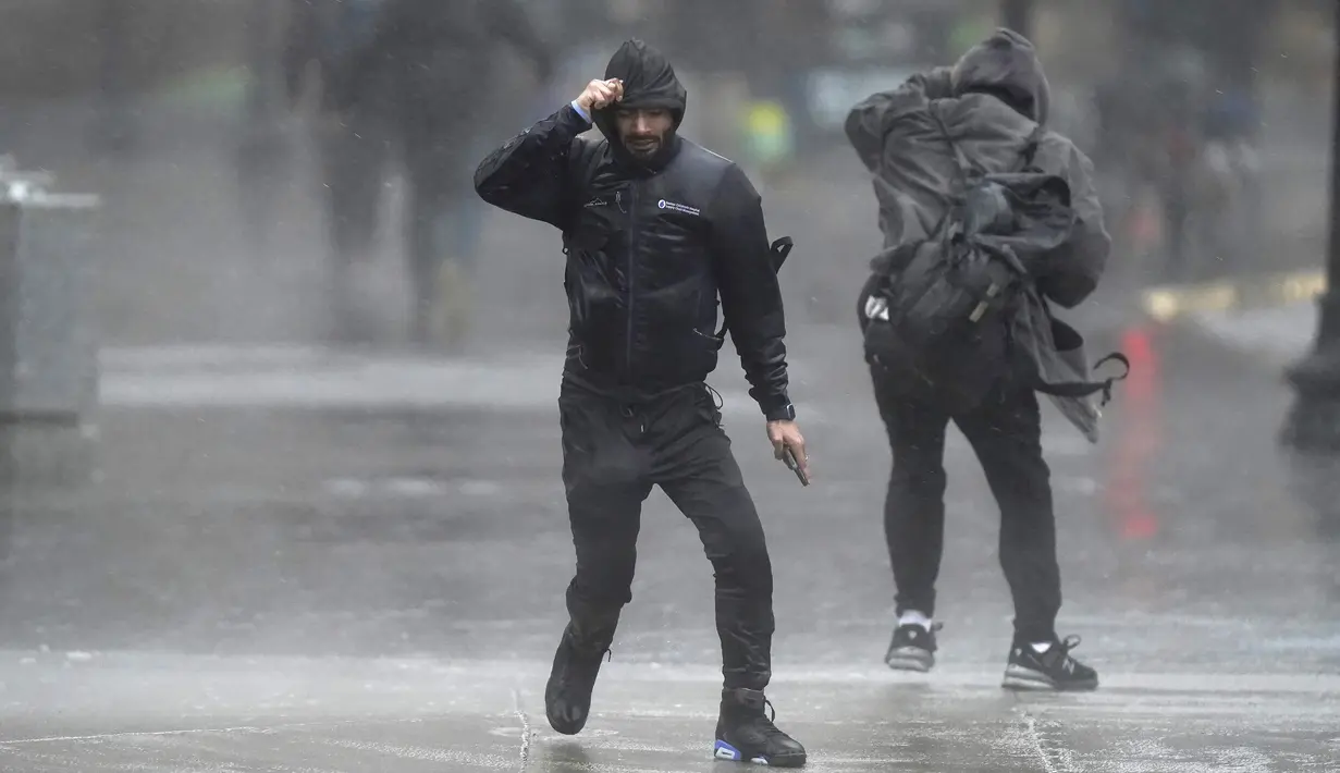 <p>Pejalan kaki diterpa angin dan hujan saat menyeberang jalan di Boston, Amerika Serikat, Senin (18/12/2023). Badai yang bergerak di Pantai Timur membawa hujan lebat dan angin kencang ke Timur Laut pada hari Senin, mengancam banjir dan memadamkan listrik ke ratusan ribu rumah. (AP Photo/Steven Senne)</p>
