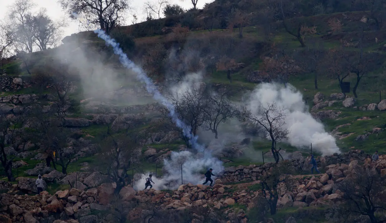 Tentara Israel menggunakan gas air mata untuk membubarkan pengunjuk rasa Palestina selama bentrokan di Desa Mughayer, Ramallah, Tepi Barat, Jumat (18/12/2020). Pengunjuk rasa Palestina yang menggunakan ketapel terlibat bentrok dengan pemukim Yahudi yang menggunakan anjing. (AP Photo/Nasser Nasser)
