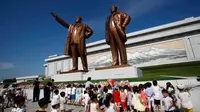 Anak-anak menaruh bunga dekat patung mendiang pemimpin Kim Il Sung dan Kim Jong Il saat memperingati 25 tahun meninggalnya Kim Il Sung di Bukit Mansu, Pyongyang, Korea Utara, Senin (8/7/2019). (AP Photo/Jon Chol Jin)
