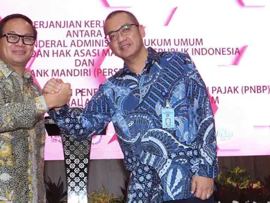 Dirut Bank Mandiri Kartika Wirjoatmodjo dan Dirjen AHU Kemenkumham Cahyo Rahadian Muzhar bersalaman usai penandatanganan perjanjian kerja sama di Jakarta, Kamis (1/8/2019). Bank Mandiri menyediakan fasilitas layanan pembayaran PNBP secara online/realtime. (Liputan6.com/Angga Yuniar)