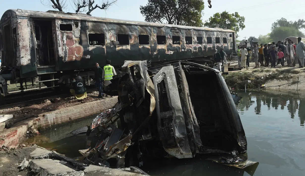 Sebuah truk hangus terbakar usai kecelakaan antara kereta penumpang dan kereta tangki minyak di Distrik Sheikhupura, Punjab, Selasa (28/3). Akibat kejadian tersebut sejumlah gerbong kereta dan kendaraan hangus terbakar. (AFP Photo / Ludovic Marin)