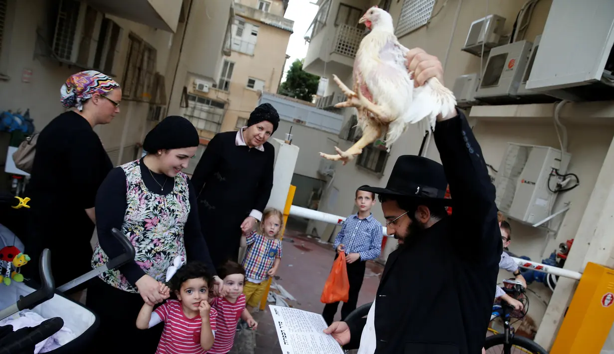 Sejumlah warga menyaksikan Pria Yahudi ultra-Ortodoks memegang ayam saat ia melakukan ritual Kaparot, di Bnei Brak, Israel, (9/10). (REUTERS/Baz Ratner)