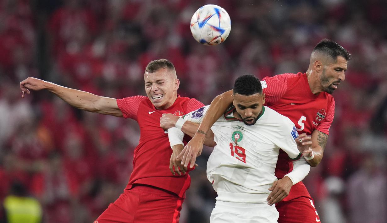 <p>Pemain Maroko,&nbsp;Youssef En-Nesyri (tenga) berebut bola dengan dua pemain Kanada, Alistair Johnston (left) and Steven Vitoria saat matchday ketiga Grup F Piala Dunia 2022 yang berlangsung di Al Thumama Stadium, Doha, Kamis (01/12/2022). (AP/Manu Fernandez)</p>