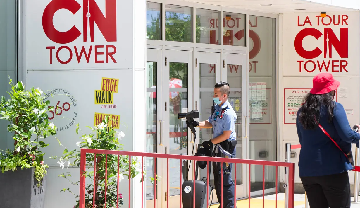 Petugas keamanan membersihkan pegangan pintu di pintu masuk CN Tower di Toronto, Kanada, pada 15 Juli 2020. Setelah ditutup akibat pandemi COVID-19, CN Tower dibuka kembali mulai Rabu (15/7), dengan pengunjung diwajibkan mengenakan masker atau penutup wajah di dalam menara tersebut. (Xinhua/Zou Zhen