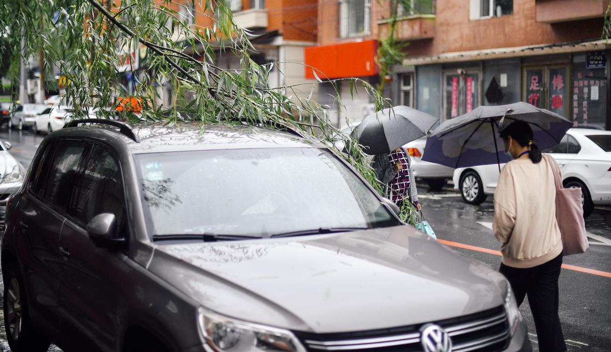Para pejalan kaki melewati dahan pohon yang patah akibat hujan badai akibat Topan Haishen di Changchun, Provinsi Jilin, China, 8 September 2020. Hujan deras melanda sebagian besar wilayah Kota Changchun sejak Senin malam waktu setempat hingga Selasa yang dipicu Topan Haishen. (Xinhua/Xu Chang)