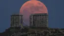 Bulan Purnama Stroberi atau Strawberry Full Moon muncul di belakang Kuil Poseidon marmer kuno di Cape Sounion, sekitar 70 Km selatan kota Athena, Yunani, Kamis (24/6/2021). Julukan ini disematkan oleh suku asli Amerika yang dipopulerkan dalam Farmers Almanac. (AP Photo/Petros Giannakouris)