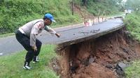 Petugas kepolisian menunjukkan kondisi jalan yang ambles akibat tanah labil di jalan penghubung Kecamatan Karangsambung-Sadang, Kabupaten Kebumen, Selasa (12/11/2024).