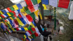 Seorang pria memasang bendera warna-warni atau yang disebut lungta pada hari ketiga Tahun Baru Tibet di Dharmsala, India (18/2). Bendera doa itu merupakan barang yang sakral sekaligus suvenir unik yang seringkali dibawa turis. (AP/Ashwini Bhatia)