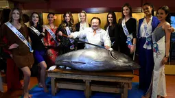 Sejumlah kontestan Miss Internasional berfoto bersama dengan Presiden Sushi-Zanmai, Kiyoshi Kimura (tengah) dan seekor tuna sirip biru seberat 250 Kg di Tokyo, Jepang (12/11). (AFP Photo/Toshifumi Kitamura)