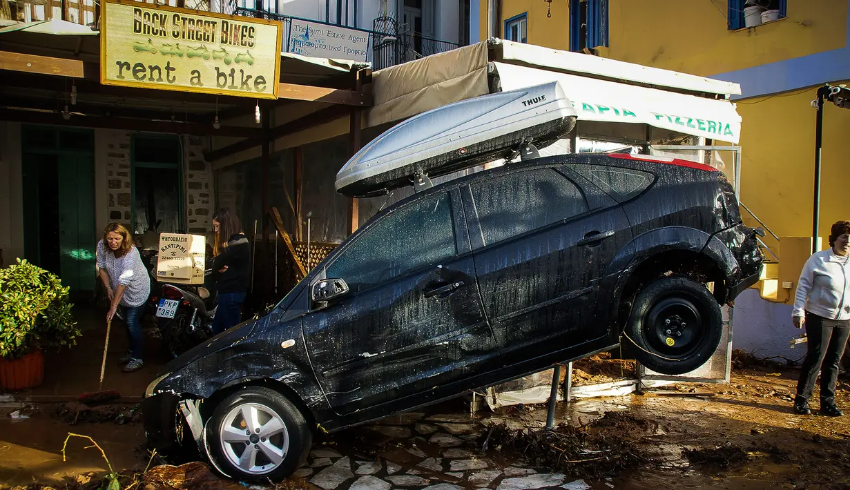 Sebuah mobil di depan toko rental kendaraan rusak akibat diterjang banjir bandang yang melanda pulau Symi di Yunani, Rabu (15/11). Banjir bandang itu melanda tiga kota terpisah di Negeri Dewa tersebut. (Argiris Madikos /Eurokinissi via AP)