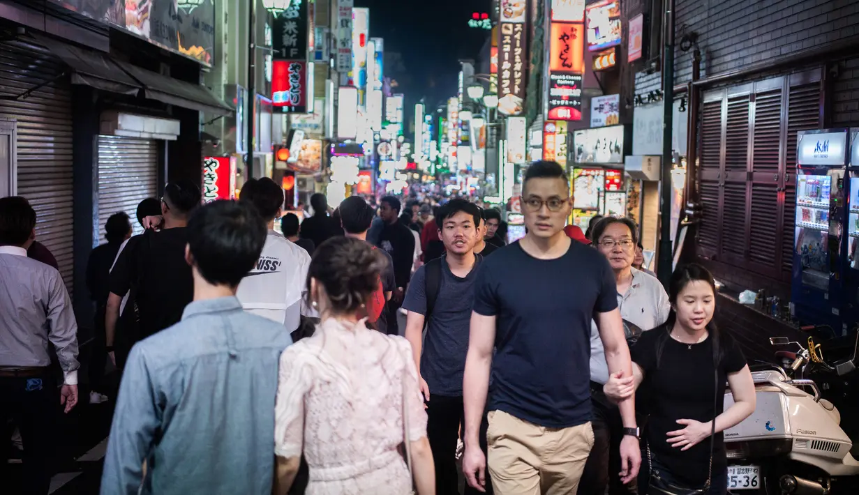 Foto yang diambil pada 22 September 2018 menunjukkan orang-orang berjalan di distrik Shinjuku, Tokyo. Distrik Shinjuku dikenal sebagai kawasan perbelanjaan dan hiburan malam Jepang. (AFP PHOTO / Martin BUREAU)