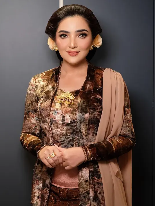 Di acara Tedak Siten Azura. Ia mengenakan kebaya velvet bernuansa coklat yang bercorak abstrak dipadu kain batik coklat sebagai rok, dan selendang coklat muda polos. [@ashanty_ash].