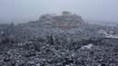 Bukit Acropolis kuno tertutup salju di Athena, Yunani, Senin (24/1/2022). Hujan salju lebat telah mengganggu lalu lintas udara di Athena dan kota tetangga terbesar di Turki, Istanbul, sementara beberapa pulau Aegea dan sebagian besar wilayah Turki diselimuti oleh salju.  (AP Photo/Michael Varaklas)