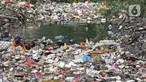Sejumlah petugas DLH mendorong sampah yang memenuhi Kali Busa untuk dikeruk menggunakan ekskavator di Tambun Utara, Kabupaten Bekasi, Jawa Barat, Jumat (10/9/2021). Pengerukan sampah ditargetkan selesai selama dua hari dan selanjutnya dipindahkan ke TPA Burangkeng. (Liputan6.com/Herman Zakharia)