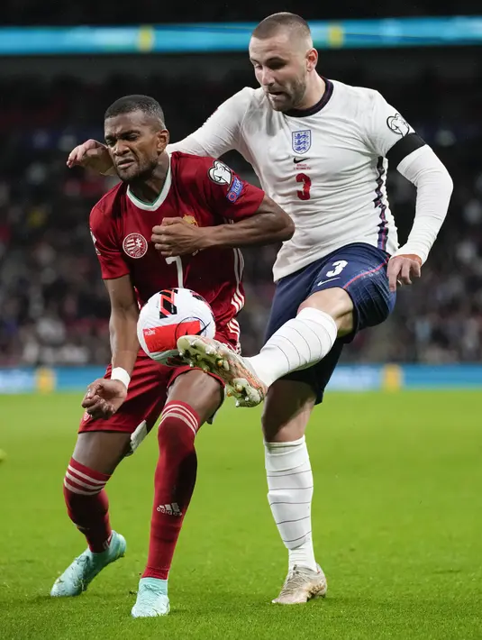 Bek Inggris Luke Shaw berebut bola dengan bek Hongaria Loic Nego pada lanjutan Kualifikasi Piala Dunia 2022 Zona Eropa Grup I di Stadion Wembley, London, Rabu (13/10/2021) dini hari WIB. Inggris harus puas bermain imbang 1-1 saat menjamu Hongaria. (AP Photo/Kirsty Wigglesworth)