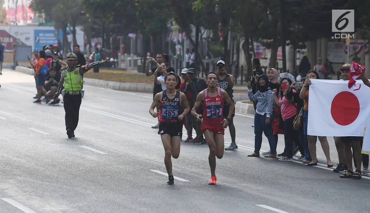 Pelari maraton Jepang, Hiroto Inoue bersaing dengan Elhassan Elabbassi dari Bahrain saat memasuki garis finis lomba Asian Games 2018 di jalan Sudirman, Jakarta, Sabtu (25/8). Hiroto menjadi pemenang lari maraton 42 kilometer. (Merdeka.com/Imam Buhori)