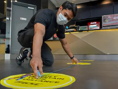 Seorang staf memasang penanda untuk mengingatkan pengunjung menjaga jarak sosial sebagai persiapan pembukaan kembali bioskop di Kuala Lumpur, Malaysia (26/6/2020). Pemerintah Malaysia mengizinkan bioskop dan teater untuk beroperasi kembali mulai 1 Juli mendatang. (Xinhua/Chong Voon Chung)