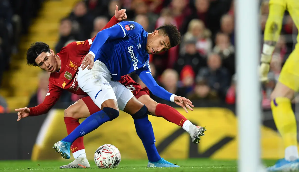 Gelandang Liverpool, Takumi Minamino berusaha merebut bola dari pemain Everton, Mason Holgate pada pertandingan babak ketiga Piala FA di Anfield, Minggu (5/1/2020). Minamino bermain selama 70 menit, lalu digantikan Alex Oxlade-Chamberlain. (AFP/Paul Ellis)