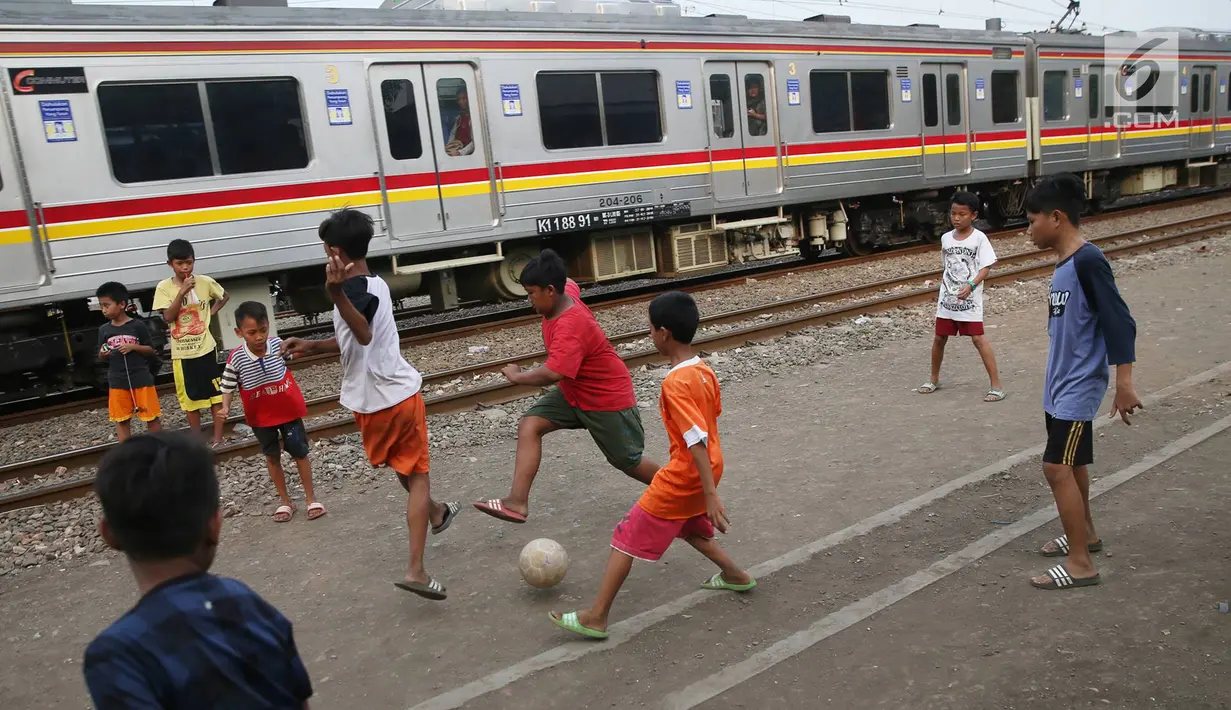 Kereta melintas di kawasan Kemayoran, Jakarta, Senin (24/7). Minimnya lahan bermain menyebabkan anak-anak terpaksa bermain di lokasi tersebut, meskipun berbahaya bagi keselamatan. (Liputan6.com/Immanuel Antonius)