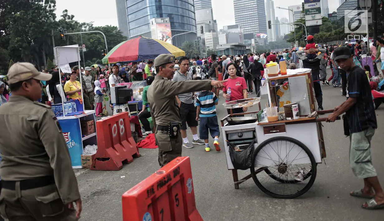Satpol PP DKI Jakarta menertibkan PKL yang berdagang di kawasan Car Free Day, Bundaran HI, Jakarta, Minggu (20/1). Penertiban dilakukan karena telah membuat ketidaknyamanan bagi para pengunjung CFD yang ingin berolahraga. (Liputan6.com/Faizal Fanani)