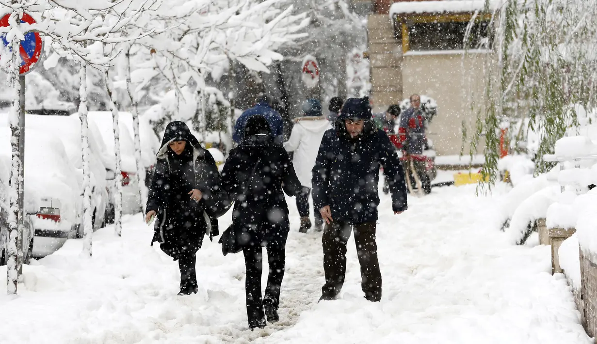 Warga Iran berjalan di tengah salju di Ibu Kota Teheran, Iran, Minggu (28/1). Menurut kantor berita resmi Iran, IRNA, sejumlah daerah pegunungan menerima salju setinggi 1,3 meter (lebih dari empat kaki). (AFP PHOTO/ATTA KENALI)