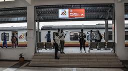 Penumpang berdiri di sebelah kereta api di stasiun kereta Kisumu, pada Jumat (17/12/2021). Kereta api Kenya melanjutkan layanan komuter antara Nairobi dan Kisumu setelah tidak beroperasi selama lebih dari 10 tahun. (Brian ONGORO/AFP)