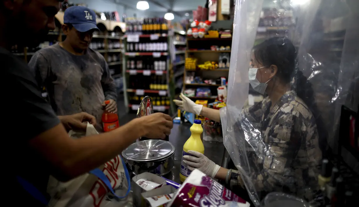 Kasir supermarket melakukan social distancing atau menjaga jarak dengan melayani pembeli lewat balik tirai palstik di Buenos Aires, Argentina, Senin (16/3/2020). Social distancing adalah cara terbaik untuk mencegah penyebaran virus corona COVID-19. (AP Photo/Natacha Pisarenko)