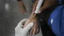 Seorang dokter merawat pasien terpapar virus Corona COVID-19  yang sedang dalam masa pemulihan di pusat kesehatan yang dikelola pemerintah di lingkungan Coche di Caracas, Venezuela pada 25 Februari 2021. (AP Photo / Matias Delacroix)