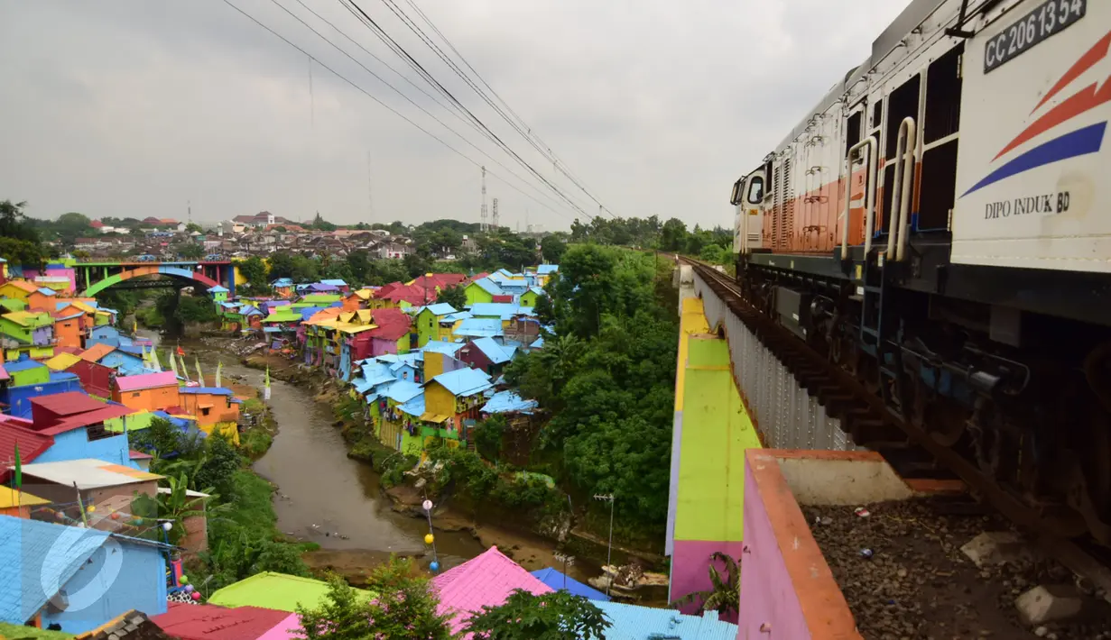 Sebuah kereta milintas di Kampung Jodipan Malang, Jawa Timur, Kamis (5/1). Kampung ini disulap menjadi sebuah pemukiman warna-warni yang menarik dan banyak wisatawan berdatangan ke tempat ini. (Liputan6.com/Gholib)