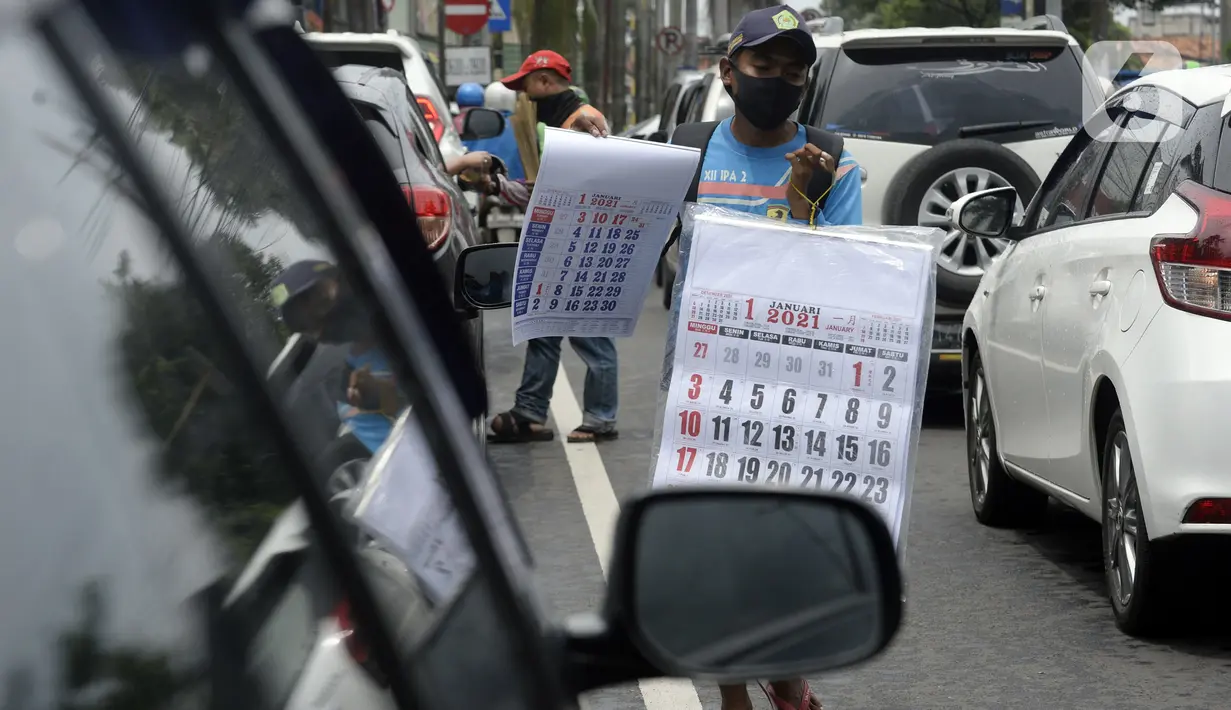Pedagang menawarkan kalender tahun 2021 kepada pengguna jalan di perempatan Pondok Pinang, Kebayoran, Jakarta Selatan, Senin (7/12/2020). Jelang pergantian tahun, sejumlah pedangang mulai menjajakan kalender tahun 2021 dengan harga Rp 20 ribu-Rp 40 ribu tergantung ukuran. (merdeka.com/Dwi Narwoko)