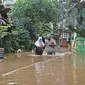 Warga berjalan melintasi banjir yang merendam kawasan Cipinang Melayu, Jakarta Timur, Jumat (19/2/2021). Banjir di kawasan tersebut akibat curah hujan yang tinggi dan meluapnya air dari Kali Sunter. (Liputan6.com/Herman Zakharia)