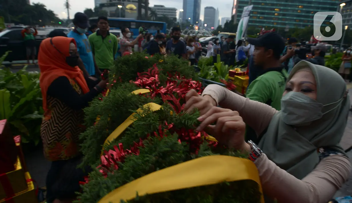 Seorang wanita menghias pohon Natal di Bundaran HI, Jakarta, Kamis (23/12/2021). Dalam rangka menyambut Natal 2021, Pemprov DKI Jakarta menggelar Christmas Carol mulai 21 hingga 23 Desember 2021. (merdeka.com/Imam Buhori)