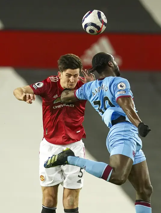 Bek Manchester United, Harry Maguire dan gelandang West Ham, Michail Antonio bersaing berebut bola pada pekan 29 Liga Inggris 2020-2021 di Old Trafford, Senin dinihari WIB (15/3/2021). Manchester United atau MU berhasil mencuri poin penuh usai kalahkan West Ham 1-0. (AP Photo/Clive Brunskill,Pool)