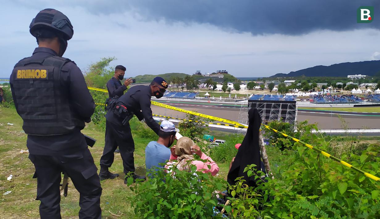 Anggota Brimob membagikan masker kepada warga yang menonton di Bukit Pongos untuk tetap menerapkan protokol kesehatan. (Bola.com/Wiwig Prayugi)