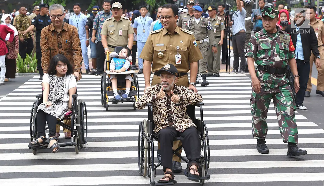 Gubernur DKI Jakarta Anies Baswedan mendorong penyandang disabilitas berkursi roda saat meresmikan pelican crossing di Halte Transjakarta Bank Indonesia (BI), Jakarta, Selasa (4/9). (Liputan6.com/Immanuel Antonius)