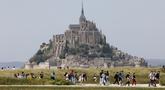 Orang-orang berjalan melewati Biara Mont-Saint-Michel saat kunjungan Presiden Prancis Emmanuel Macron di Normandia, Le Mont-Saint-Michel, Prancis, Senin (5/6/2023). (Ludovic MARIN/POOL/ AFP)