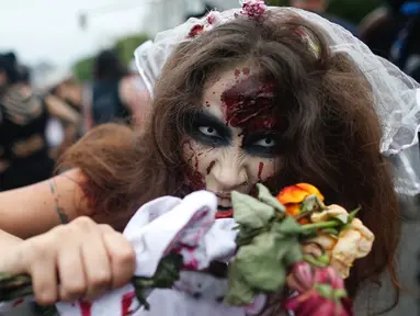Seorang wanita memakai kostum dan dandanan menyerupai zombie dalam acara Zombie Walk di pantai Copacabana, Rio de Janeiro, Brasil, Jumat (2/11). Ribuan orang ini beraksi sebagai Zombie untuk memeriahkan peringatan Hari Para Arwah. (Mauro PIMENTEL/AFP)