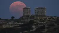 Bulan Purnama Stroberi atau Strawberry Full Moon muncul di belakang Kuil Poseidon marmer kuno di Cape Sounion, sekitar 70 Km selatan kota Athena, Yunani, Kamis (24/6/2021). Strawberry Full Moon adalah istilah yang diambil dari cerita tradisi dari suku-suku asli Amerika (AP Photo/Petros Giannakouris)