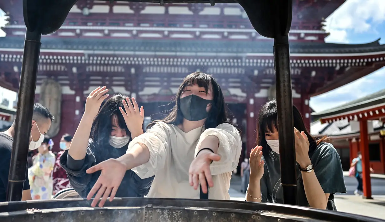 Sejumlah wanita berkumpul di sekitar pembakar dupa besar untuk mengepulkan asap ke arah diri mereka sendiri selama kunjungan ke kuil Sensoji di distrik Asakusa Tokyo (22/9/2020). (AFP/Charly Triballeau)