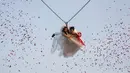 Jintara Promchat dan Kittinant Suwansiri bergelantungan pada tali saat upacara pernikahan di Ratchaburi, Thailand, Sabtu (13/2). Upacara pernikahan tersebut diikuti oleh empat pasang pengantin untuk menyambut Hari Valentine. (REUTERS/ Athit Perawongmetha)