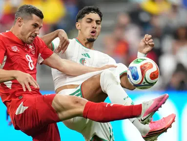 Pemain Swiss Remo Freuler berebut bola dengan pemain Aljazair Fares Chaibi selama pertandingan sepak bola babak 32 Piala Dunia antara Swiss dan Aljazair di Vancouver, British Columbia, (AP Photo/Abbie Parr)