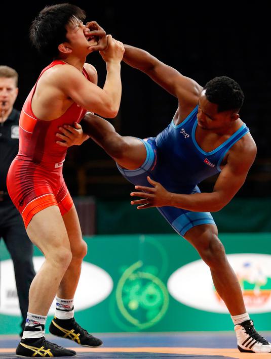 Kazuya Koyanagi dari Jepang (kiri) saat bertanding melawan Yowlys Bonne Rodriguez dari Kuba selama pertandingan gulat 61 kilogram di Freestyle Wrestling World Cup di Iowa City, Iowa (8/4). (AP Photo/Charlie Neibergall)