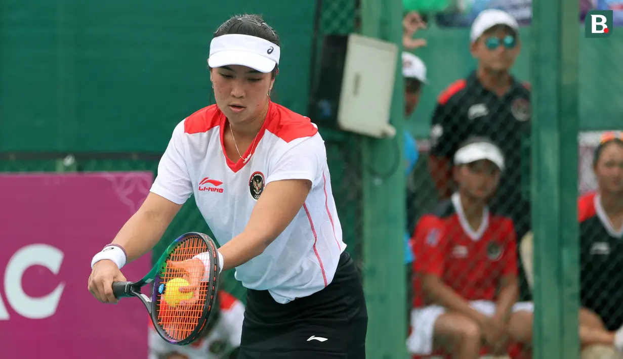 Petenis putri Indonesia, Aldila Sutjiadi melakukan servis ke arah petenis Thailand, Aunchisa Chanta pada pertandingan final tenis beregu putri SEA Games 2023 di Tennis Arena, Morodoc Techo National Stadium, Phnom Penh, Kamboja, Selasa (9/5/2023). Indonesia sempat tertinggal di partai pertama namun sukses menyamakan kedudukan saat partai kedua. Pasangan Aldila dan Jessy kemudian sukses menyegel kemenangan partai ketiga sekaligus memberikan emas ke-24 untuk Indonesia. (Bola.com/Abdul Aziz)