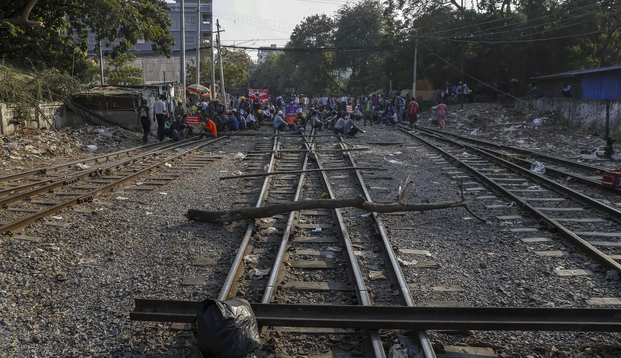 Demonstran duduk di rel kereta api setelah memblokir rel kereta api selama protes terhadap kudeta militer di Mandalay, Myanmar (17/2/2021). Aksi protes tersebut menghentikan layanan kereta api antara Yangon dan kota selatan Mawlamyine. (AP Photo)