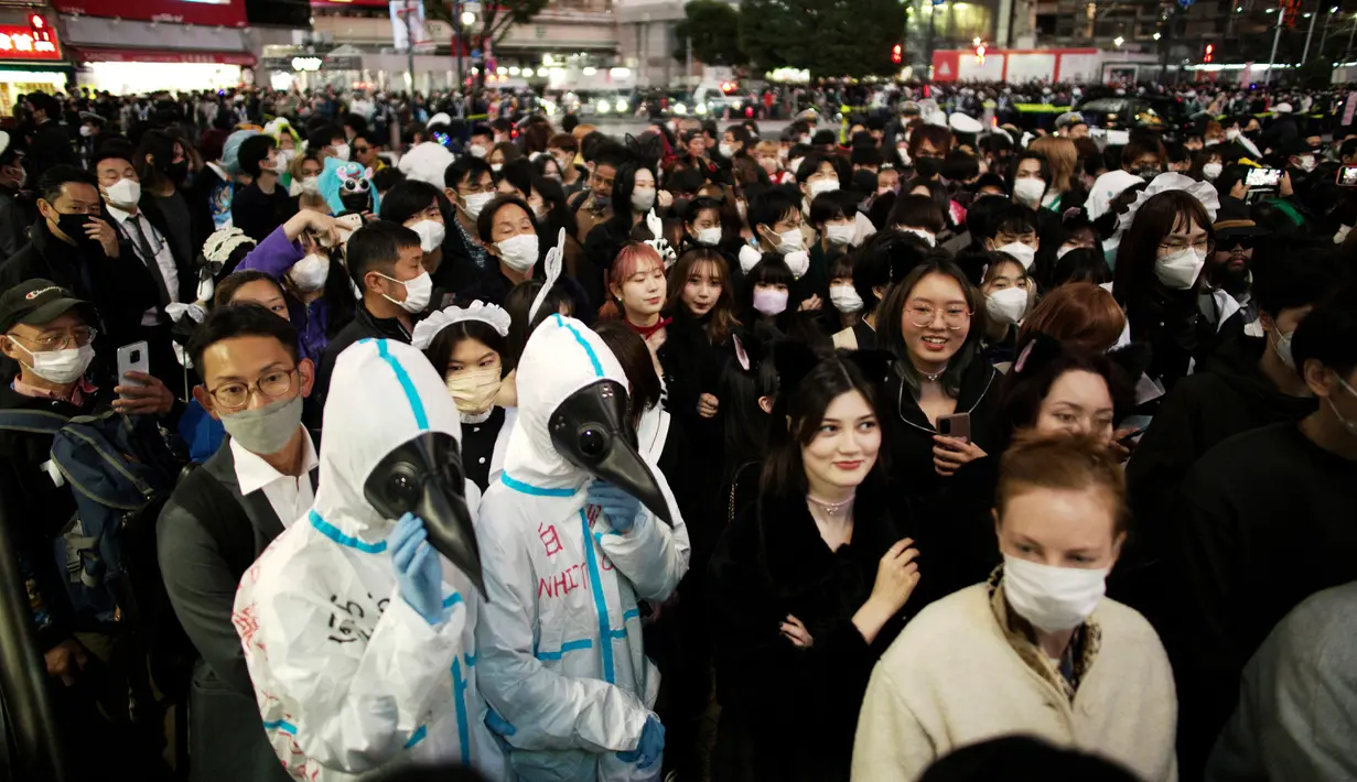 Orang-orang dengan kostum berjalan menyeberangi persimpangan jalan yang terkenal saat perayaan Halloween di distrik hiburan Shibuya, Tokyo, Jepang, 31 Oktober 2022. Polisi mengarahkan pejalan kaki untuk tetap berjalan dan tidak berdiri di satu area, karena banyak yang berhenti untuk mengambil video atau foto. (AP Photo/Hiro Komae)