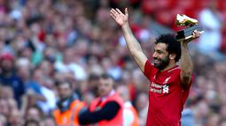 Mohamed Salah mengangkat penghargaan Sepatu Emas yang diraihnya setelah Liverpool menekuk Brighton and Hove Albion di Anfield, Minggu (13/5). Salah menyumbangkan 32 gol, unggul dua gol dari bomber Tottenham Hotspur, Harry Kane. (Dave Thompson/PA via AP)